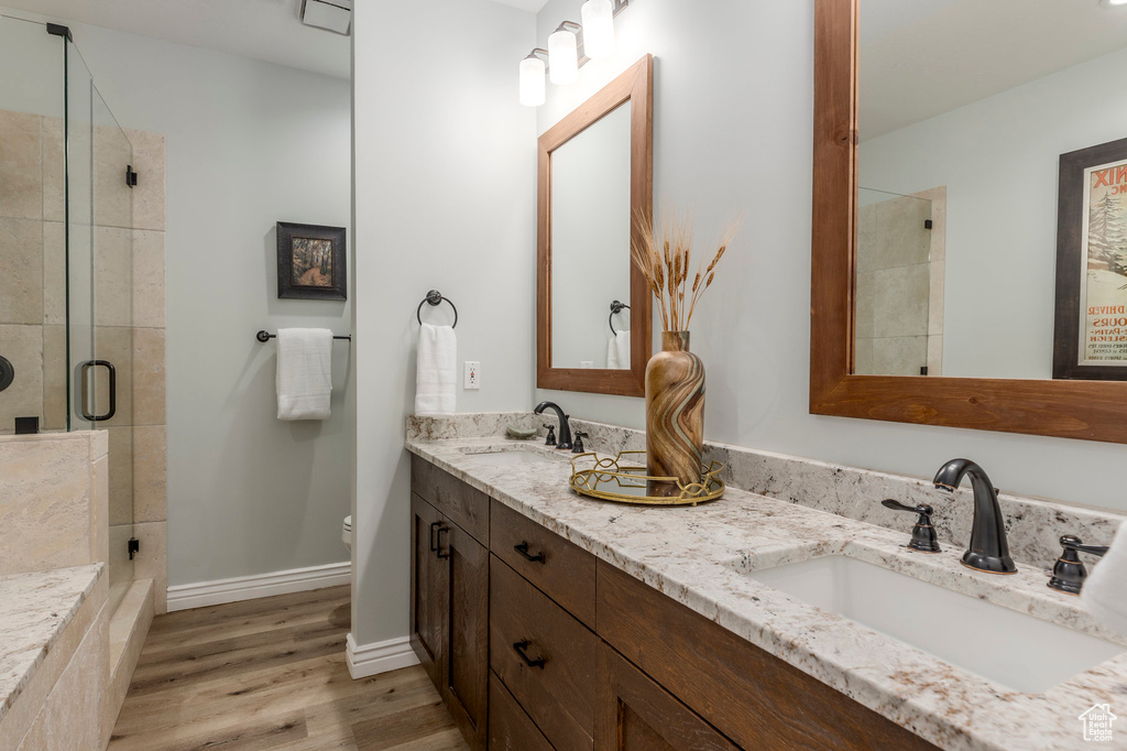 Full bathroom featuring a stall shower, wood finished floors, toilet, and double vanity