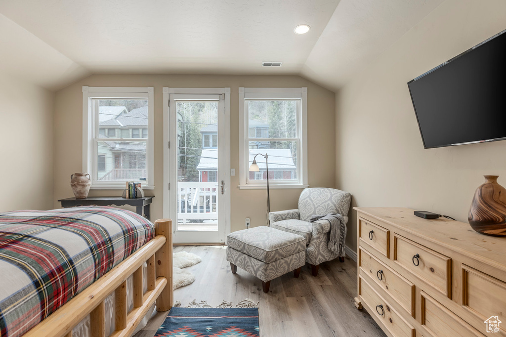 Bedroom with lofted ceiling, access to exterior, multiple windows, and wood finished floors