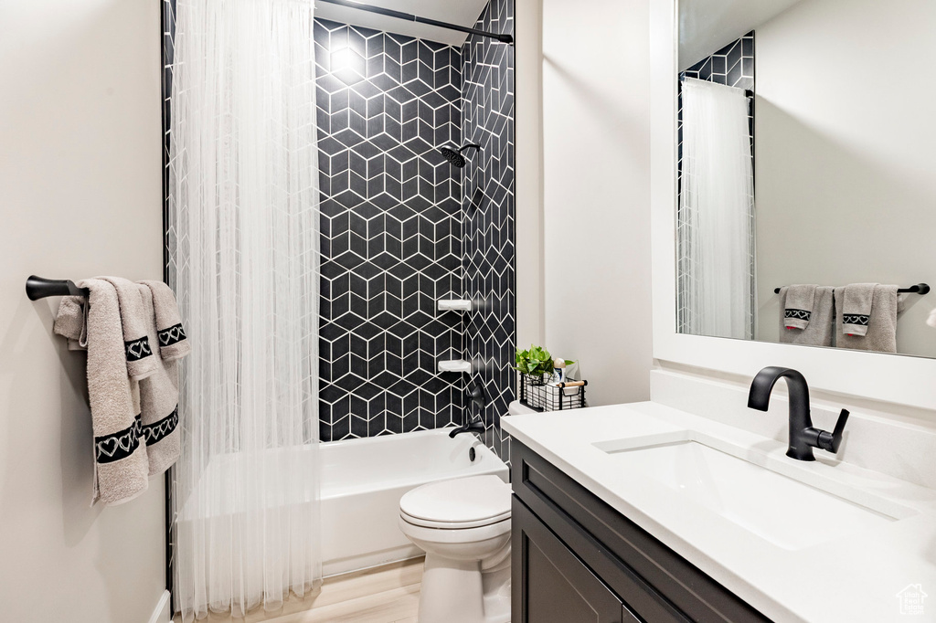 Bathroom featuring toilet, vanity, and shower / bath combo