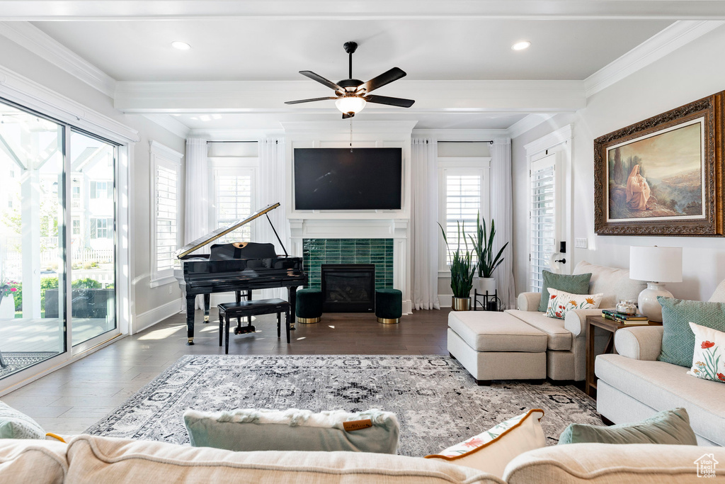 Living area with crown molding, ceiling fan, wood finished floors, a tiled fireplace, and baseboards