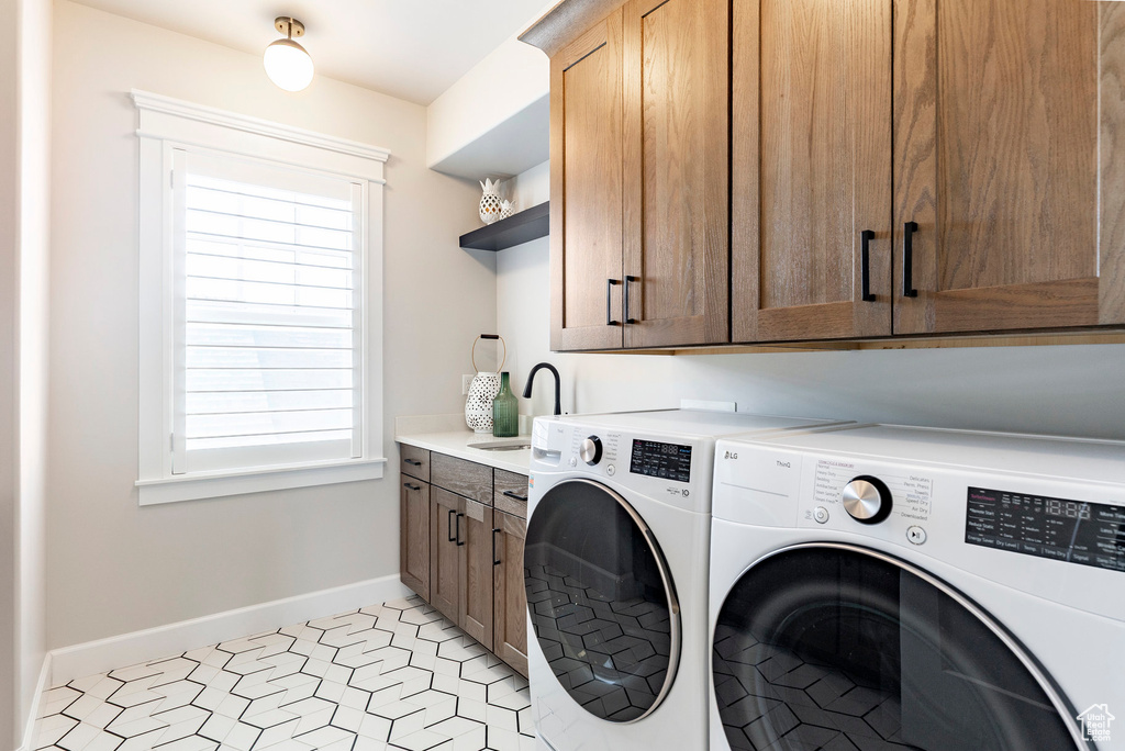 Laundry room with independent washer and dryer, cabinet space, baseboards, and healthy amount of natural light