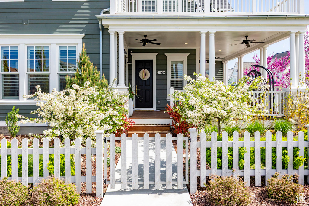 Property entrance with a ceiling fan, fence, and covered porch