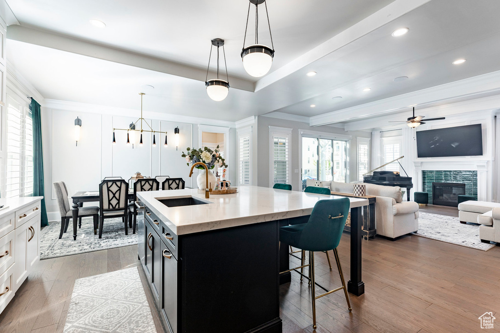 Kitchen with a sink, a breakfast bar, ornamental molding, dark cabinetry, and decorative light fixtures