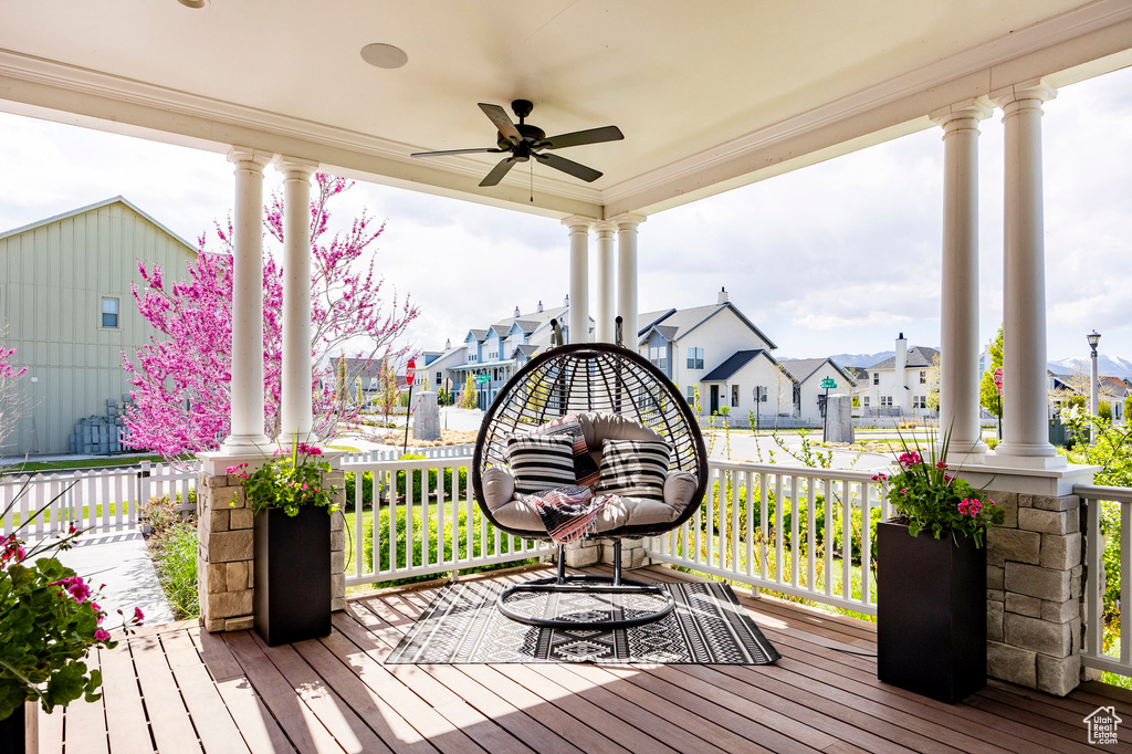 Wooden terrace featuring covered porch, a ceiling fan, and a residential view