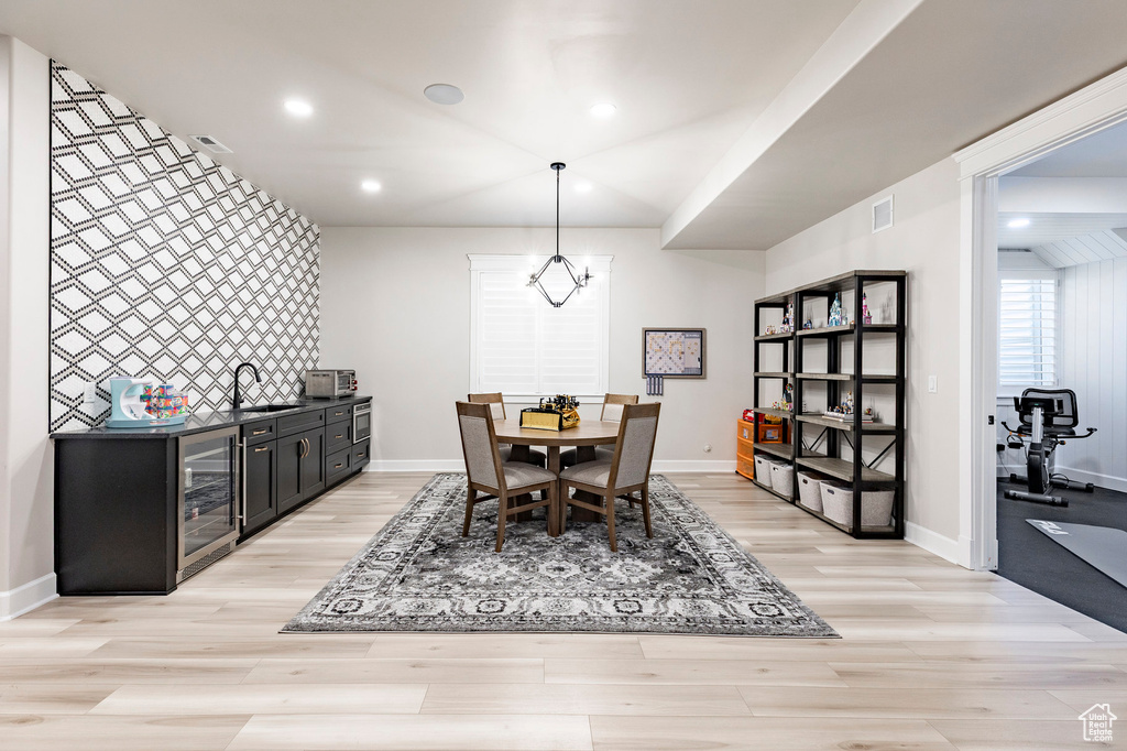 Dining space featuring wine cooler, light wood finished floors, baseboards, and recessed lighting