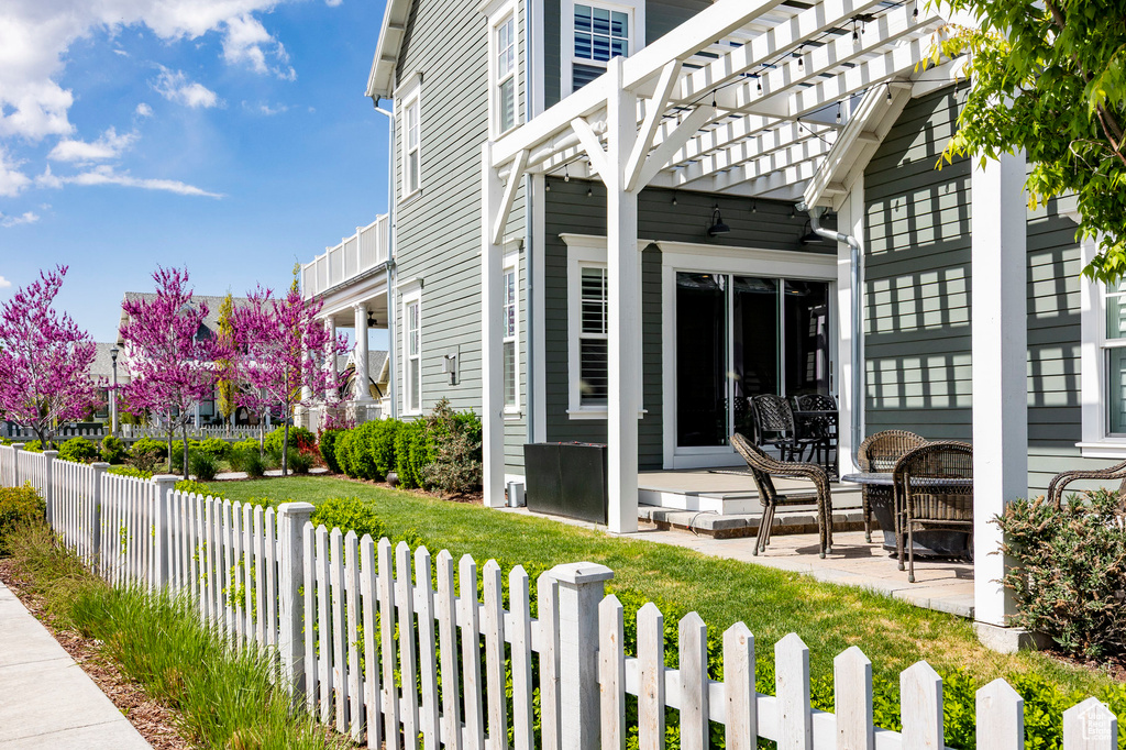View of patio with a fenced front yard and a pergola