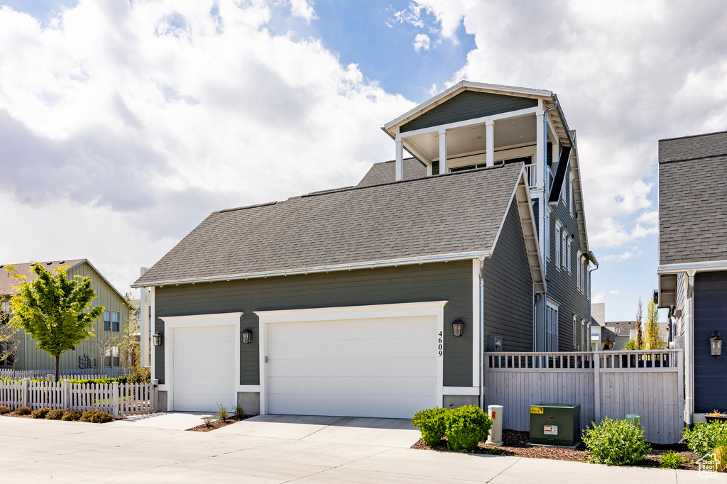 View of front of home with fence, a shingled roof, driveway, and an attached garage