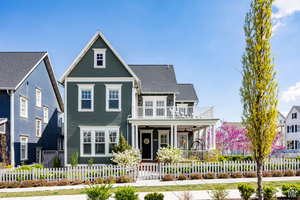View of front of home with covered porch, a fenced front yard, a balcony, and a ceiling fan