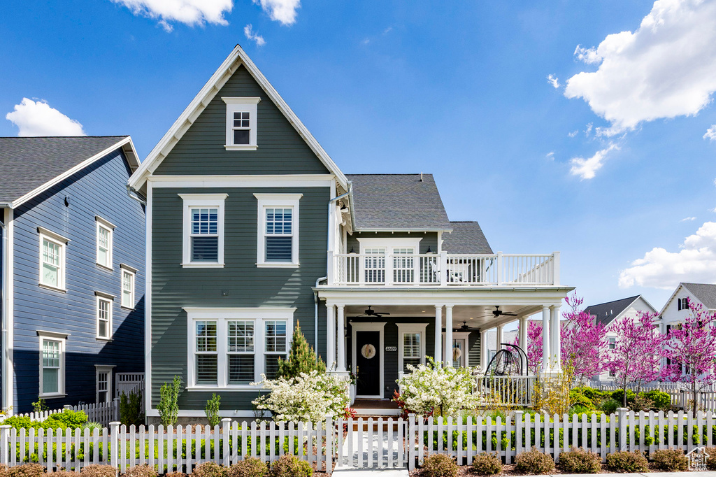View of front of home with a porch, ceiling fan, a fenced front yard, and a balcony