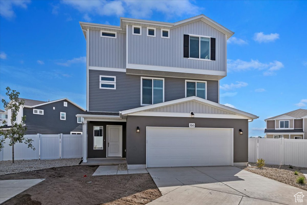 View of front of house featuring fence, driveway, and a garage