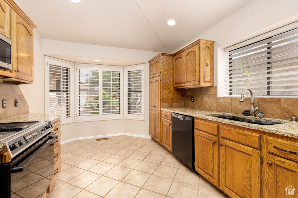 Kitchen with dishwasher, electric stove, a sink, tasteful backsplash, and light stone countertops