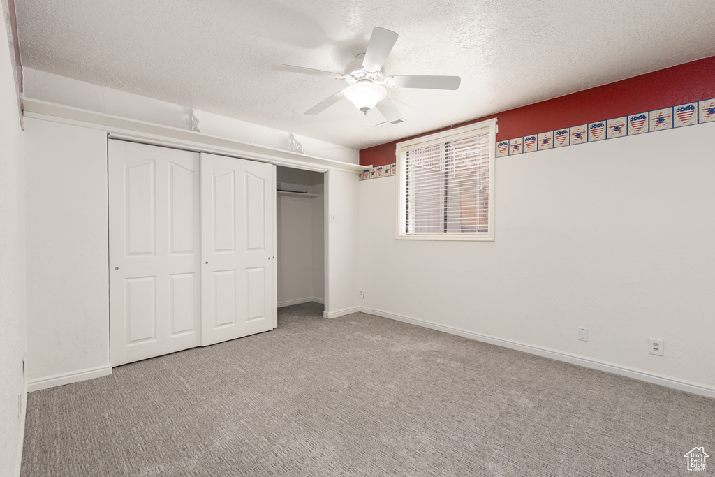 Unfurnished bedroom with a closet, carpet floors, a textured ceiling, a ceiling fan, and baseboards