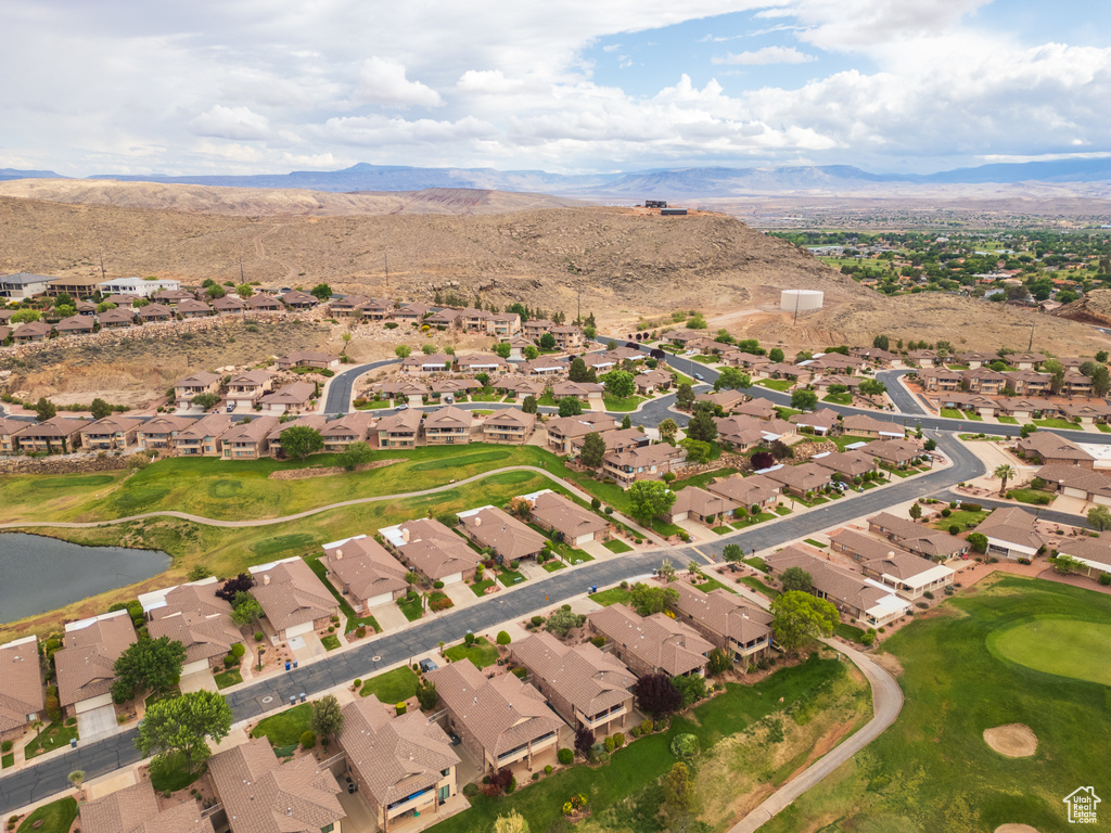 Aerial view of property and surrounding area with nearby suburban area, a golf club, and a water and mountain view