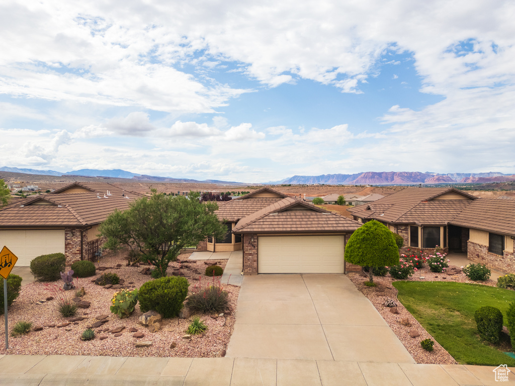 View of front facade with a tiled roof, a garage, driveway, and a mountain view