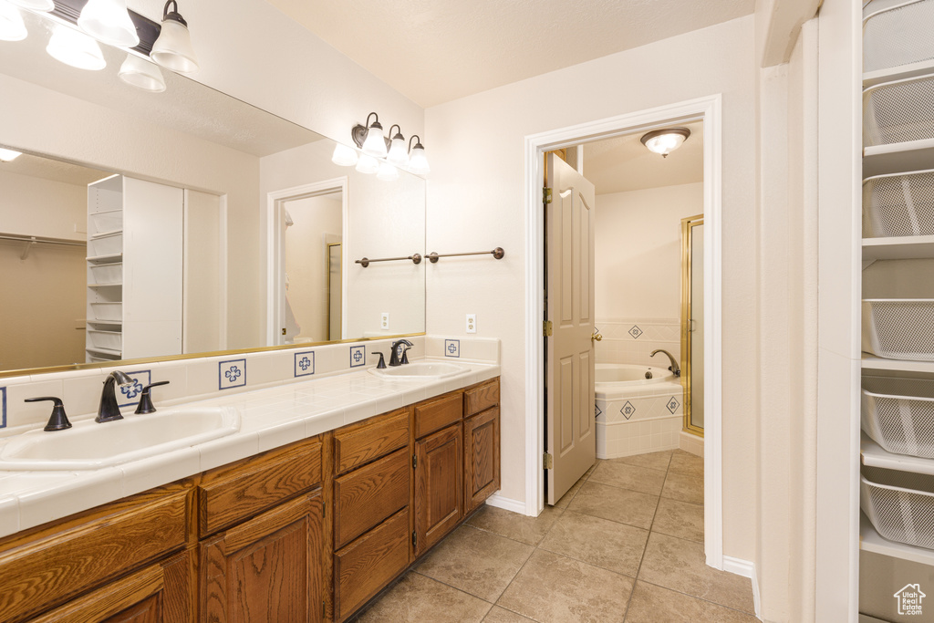 Bathroom with tile patterned floors, a walk in closet, double vanity, and a bathtub