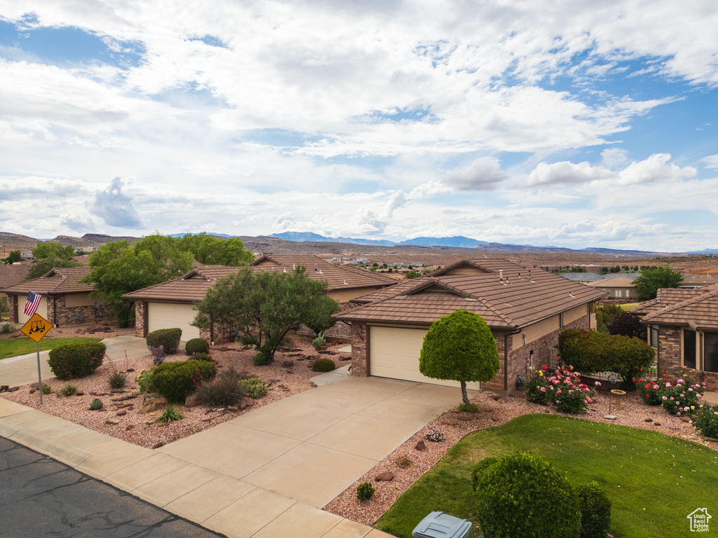 View of front facade featuring a tile roof, concrete driveway, a mountain view, and a residential view