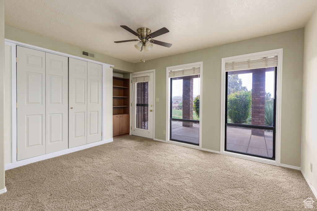 Unfurnished bedroom with access to outside, carpet, baseboards, a ceiling fan, and a textured ceiling
