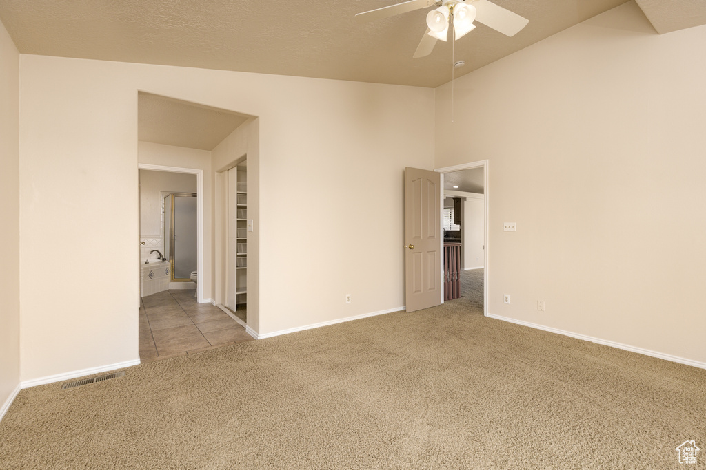 Unfurnished room featuring carpet floors, ceiling fan, baseboards, and vaulted ceiling
