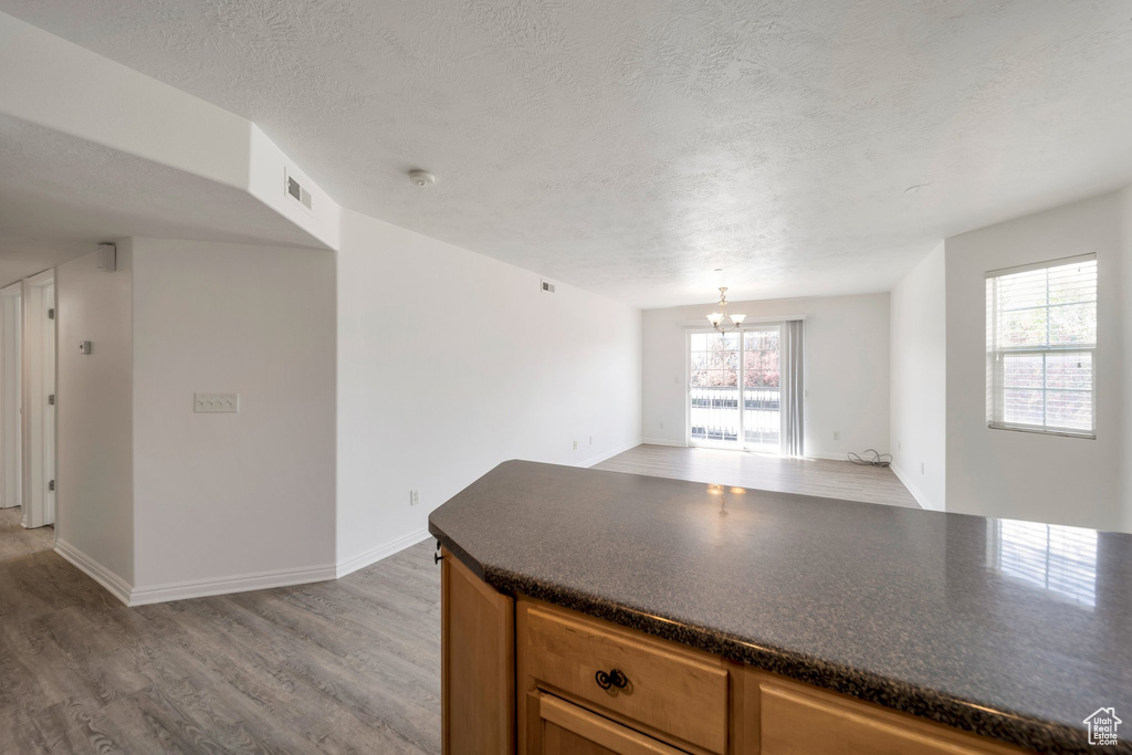 Kitchen featuring light wood-type flooring, dark countertops, visible vents, and a textured ceiling