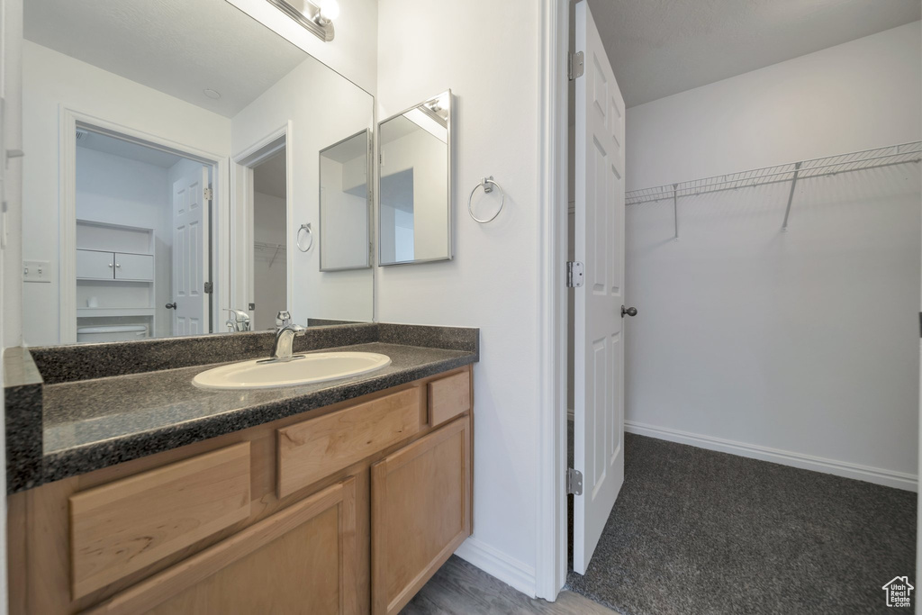 Bathroom featuring a spacious closet, baseboards, and vanity