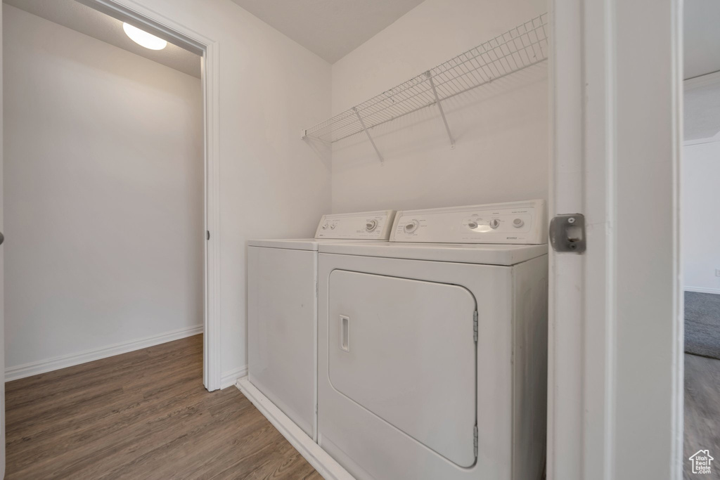 Washroom with separate washer and dryer, baseboards, wood finished floors, and laundry area