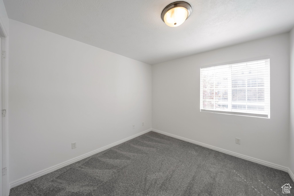 Empty room with baseboards and dark carpet
