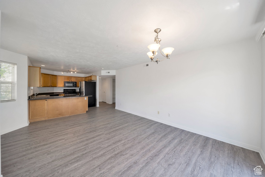 Kitchen with open floor plan, freestanding refrigerator, light wood-style floors, and dark countertops