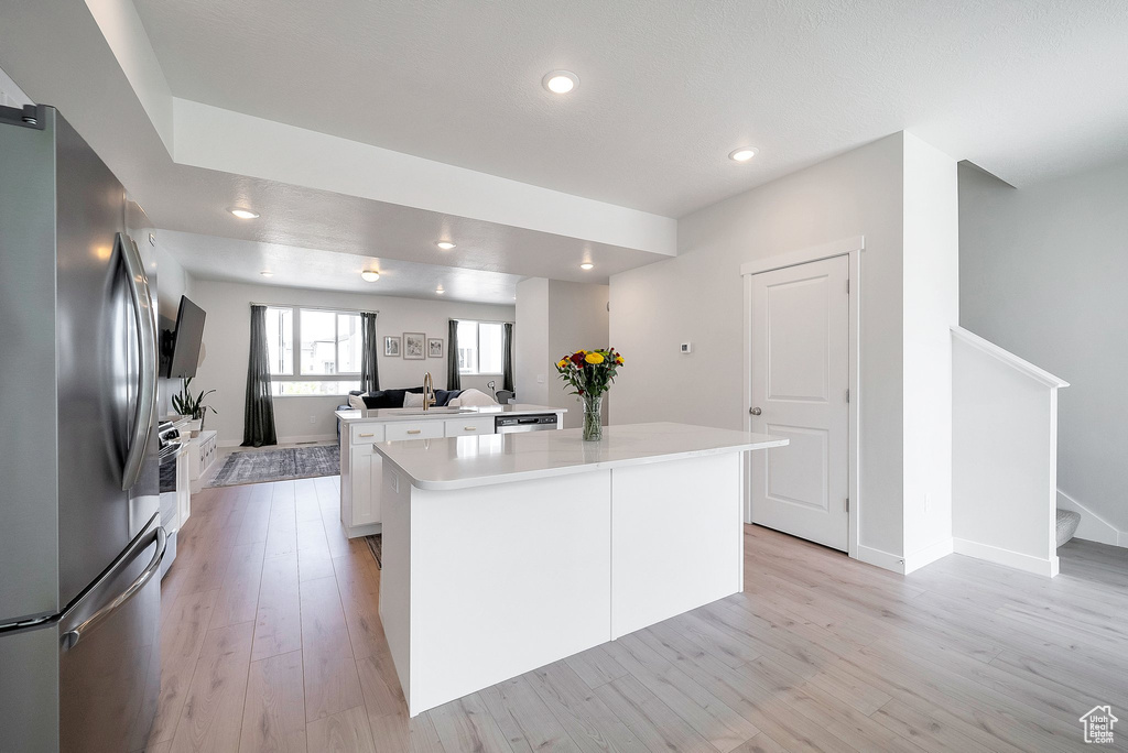 Kitchen with appliances with stainless steel finishes, a center island, light wood-style flooring, white cabinets, and recessed lighting