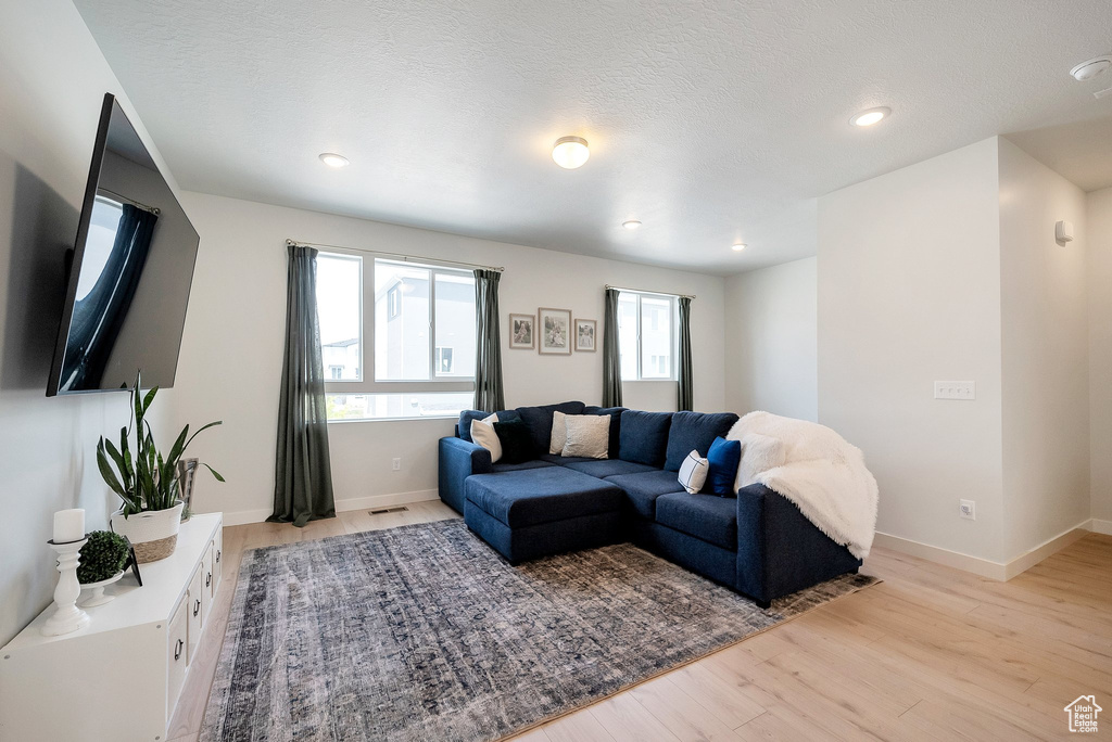 Living area with light wood-style floors, baseboards, and recessed lighting