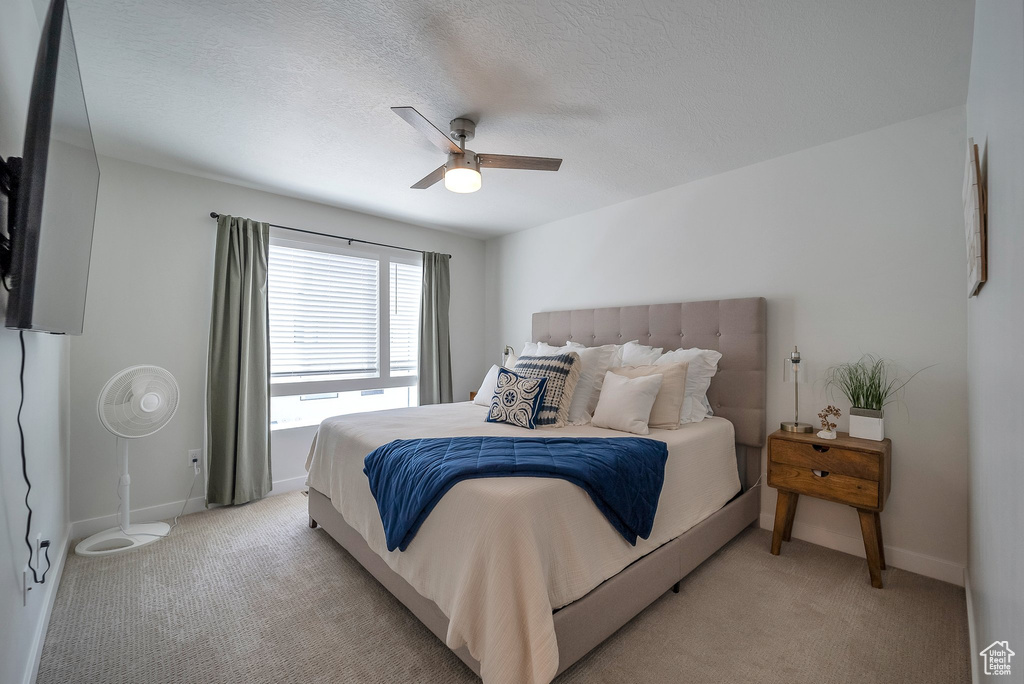 Bedroom with light carpet, baseboards, a ceiling fan, and a textured ceiling