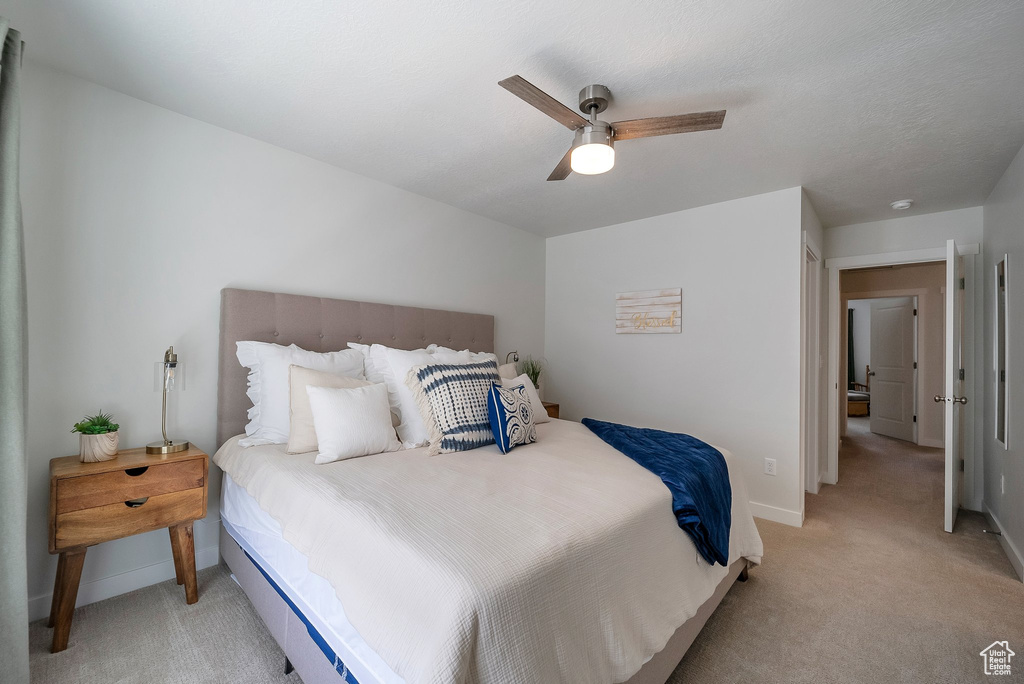 Bedroom with light colored carpet, baseboards, and a ceiling fan
