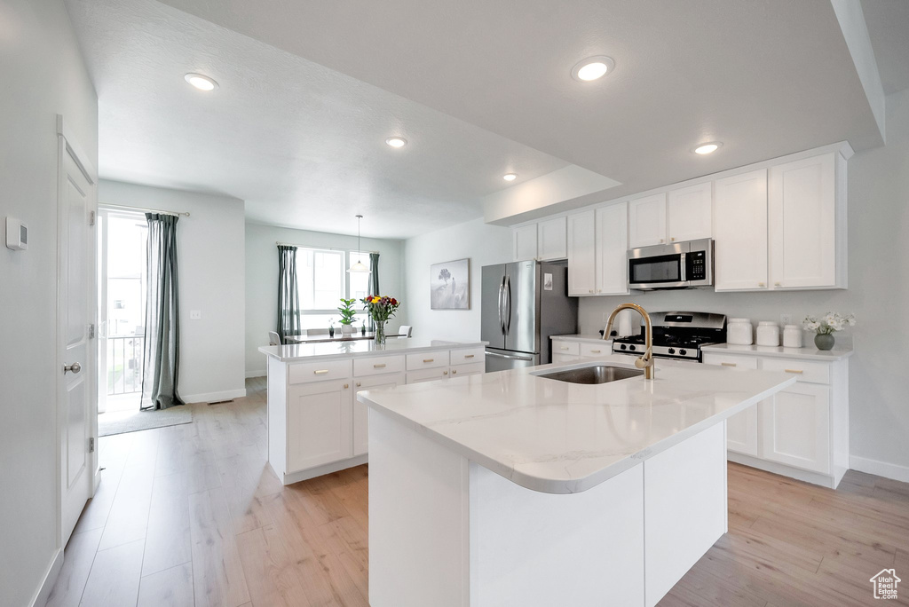 Kitchen featuring appliances with stainless steel finishes, a kitchen island with sink, a sink, baseboards, and recessed lighting