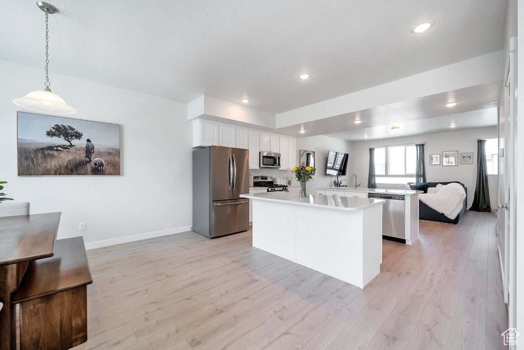 Kitchen with appliances with stainless steel finishes, light countertops, white cabinetry, light wood-style floors, and recessed lighting