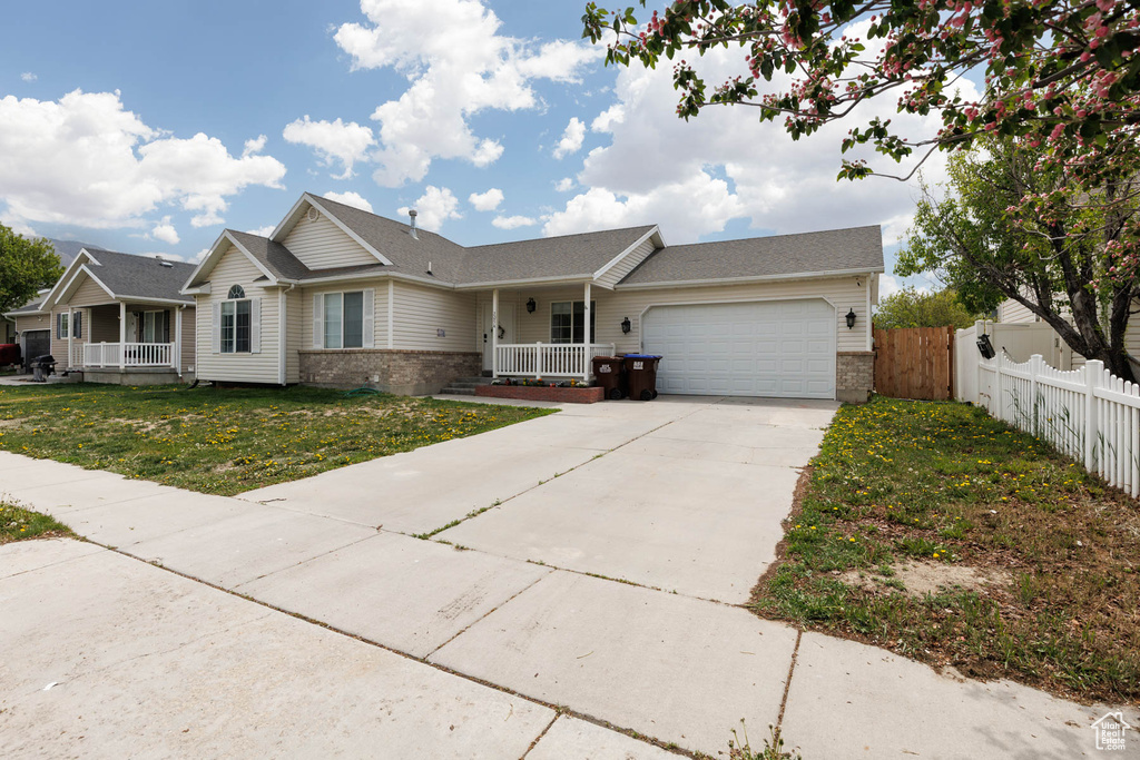 Ranch-style house with brick siding, an attached garage, driveway, and a porch