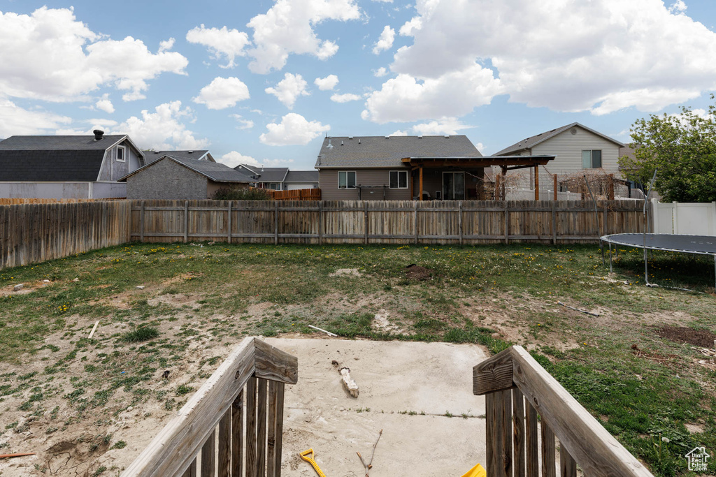 Fenced backyard featuring a trampoline