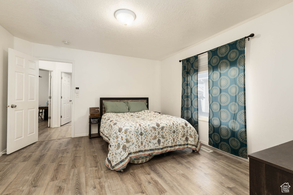 Bedroom with wood finished floors, baseboards, and a textured ceiling