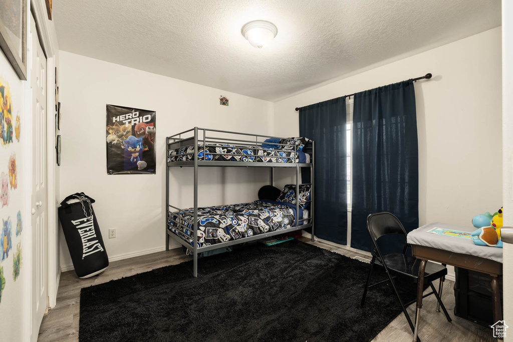 Bedroom with wood finished floors, baseboards, and a textured ceiling