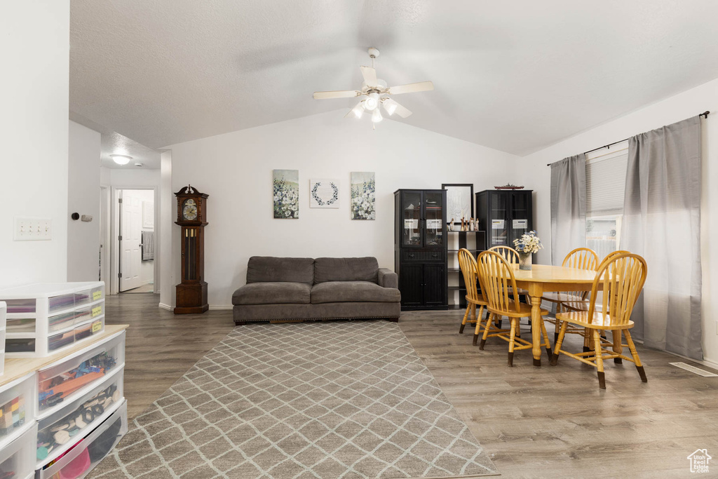 Living room featuring vaulted ceiling, light wood-style flooring, ceiling fan, and baseboards