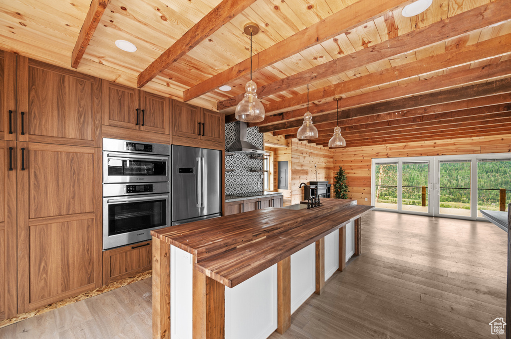 Kitchen featuring butcher block counters, appliances with stainless steel finishes, wooden ceiling, light wood-style floors, and beam ceiling