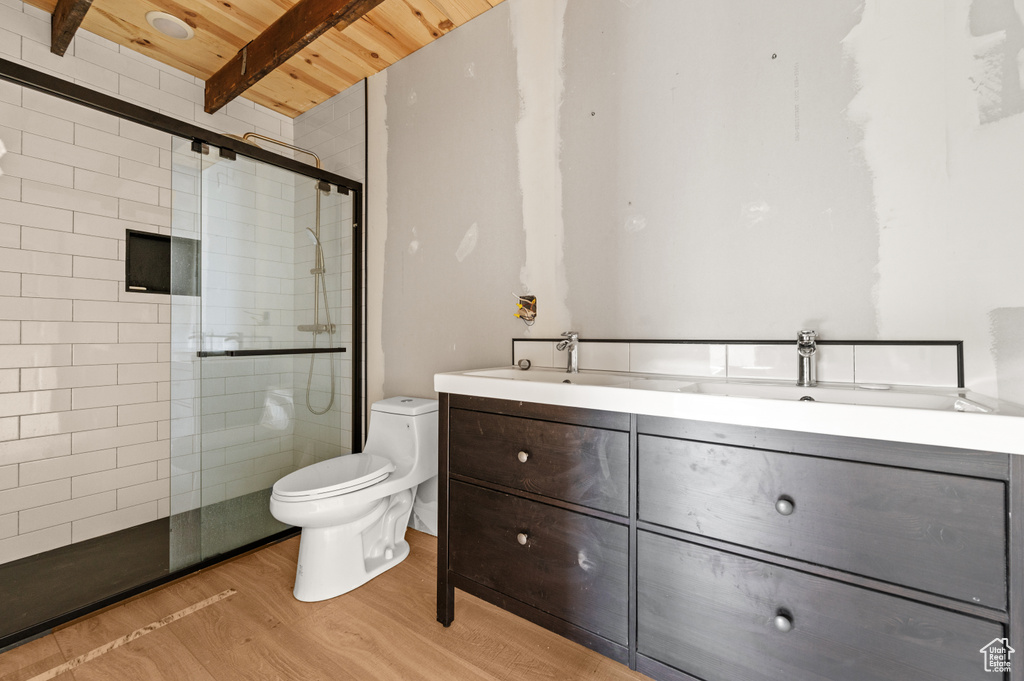 Bathroom featuring wood ceiling, a tile shower, toilet, wood finished floors, and double vanity