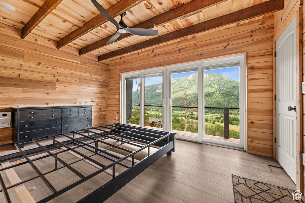 Bedroom featuring wooden ceiling, wooden walls, beam ceiling, multiple windows, and hardwood / wood-style floors
