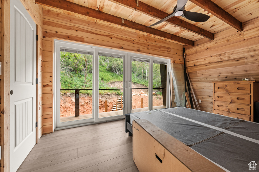 Bedroom featuring wood ceiling, wooden walls, beamed ceiling, multiple windows, and light wood finished floors