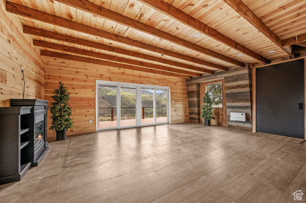 Unfurnished living room featuring beam ceiling, wooden ceiling, wood walls, and light wood finished floors