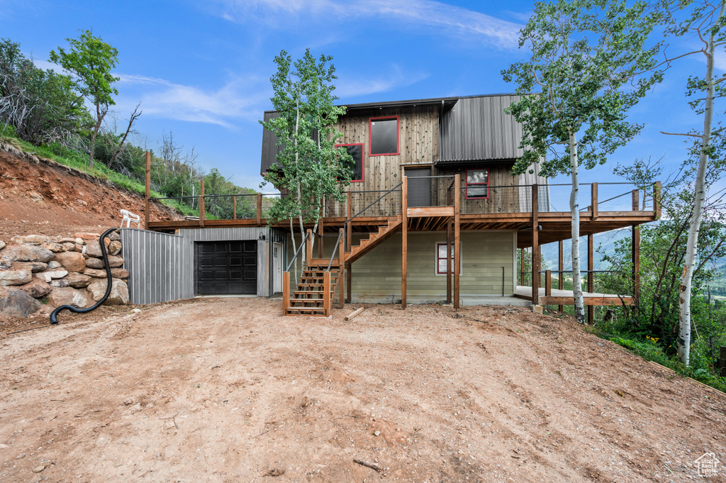 View of front of house with driveway, stairway, a deck, and an attached garage