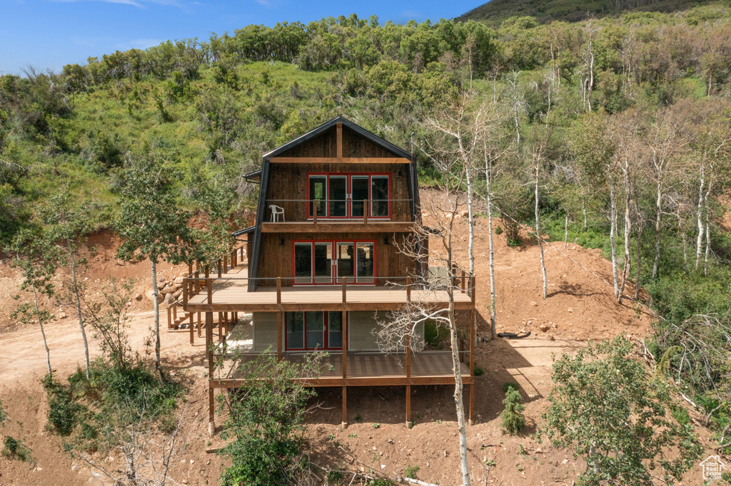 Back of property with a balcony and a view of trees