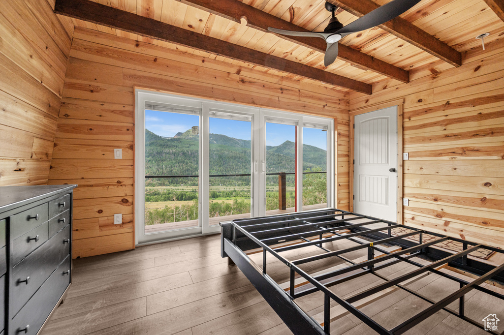 Bedroom featuring wood walls, wood ceiling, beam ceiling, a mountain view, and wood-type flooring