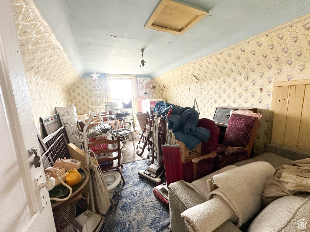 Additional living space with wallpapered walls, attic access, and lofted ceiling