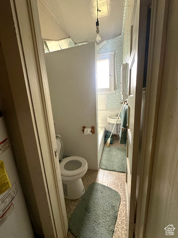 Bathroom featuring toilet, water heater, and a bathtub