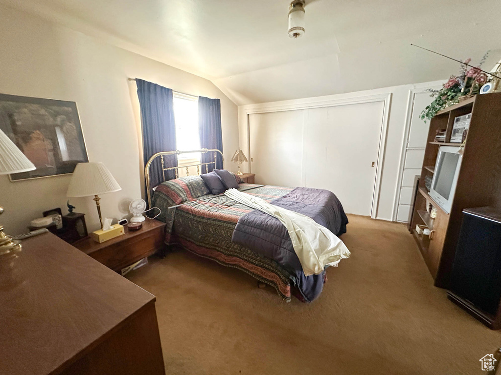 Bedroom featuring vaulted ceiling, carpet flooring, and a closet