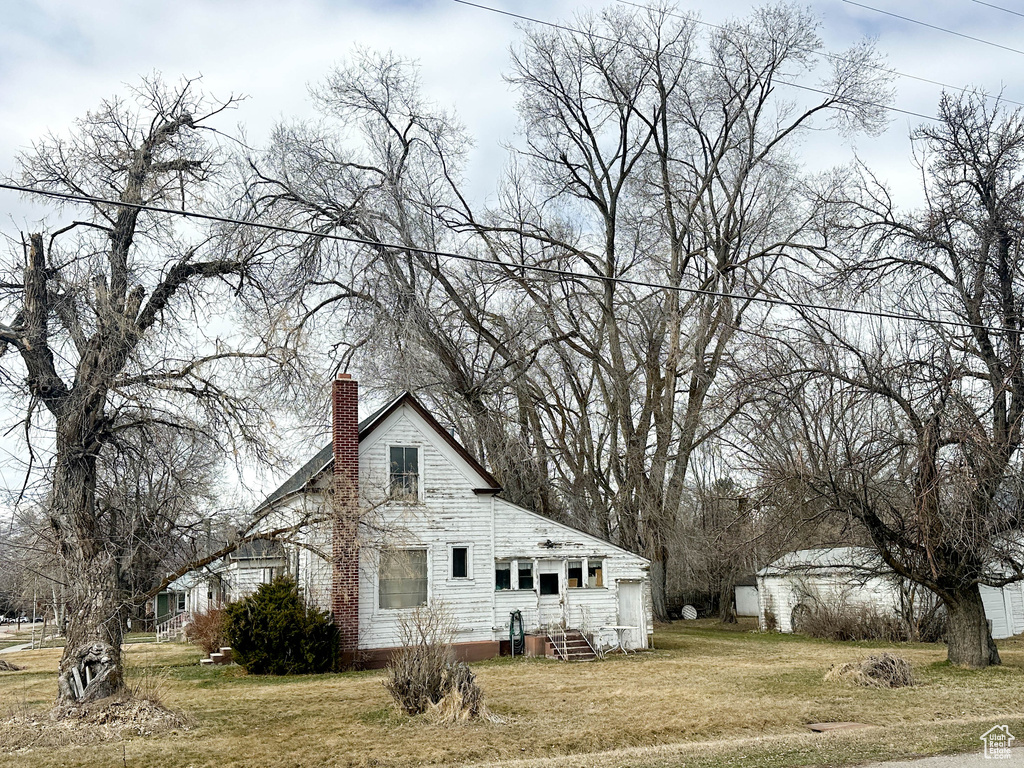 View of home's exterior featuring a chimney, a lawn, and entry steps